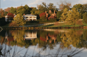 Photo of looking over the lake at Barboursville Vineyards to see the 1804 Inn. Barboursville Ruins and colorful fall foliage reflected on the water.