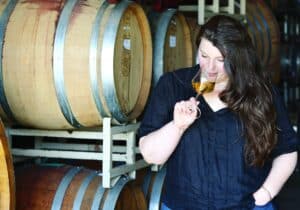 Maya Hood White Early Mountain Vineyard Female Winemaker tasting white wine in barrel room.