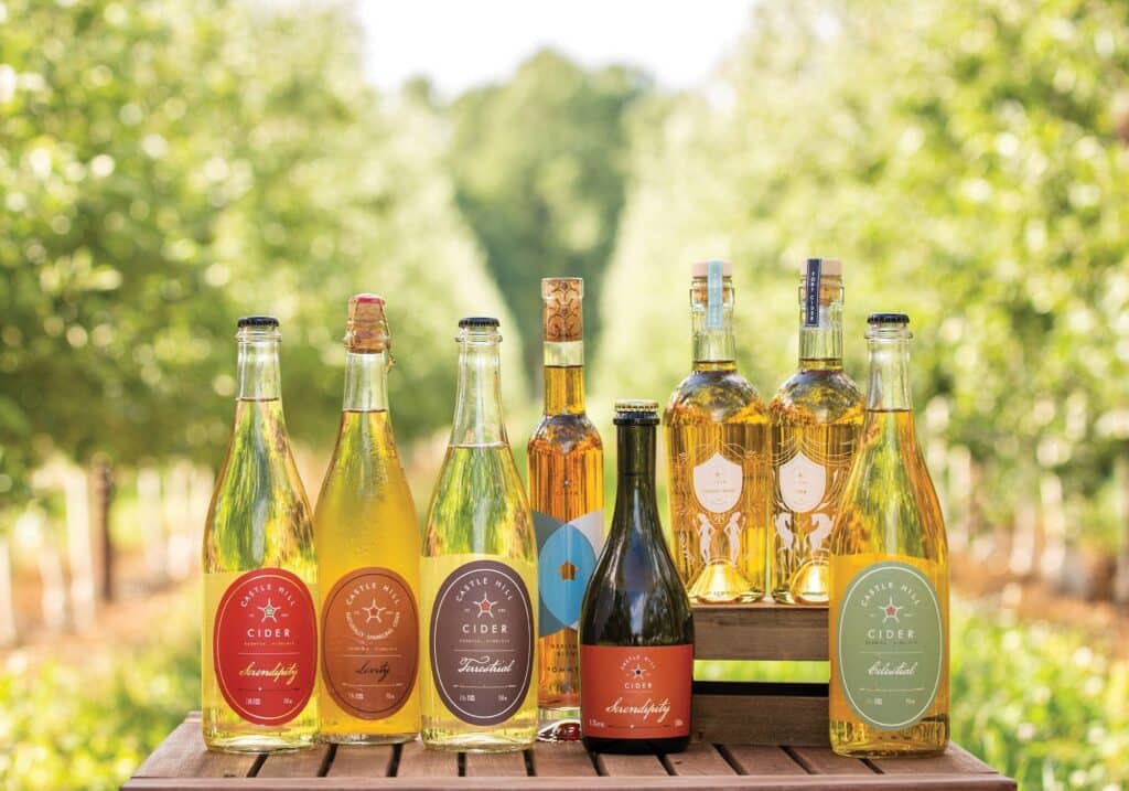 Photo of various ciders from Castle Hill Cider on a table among the fruit trees