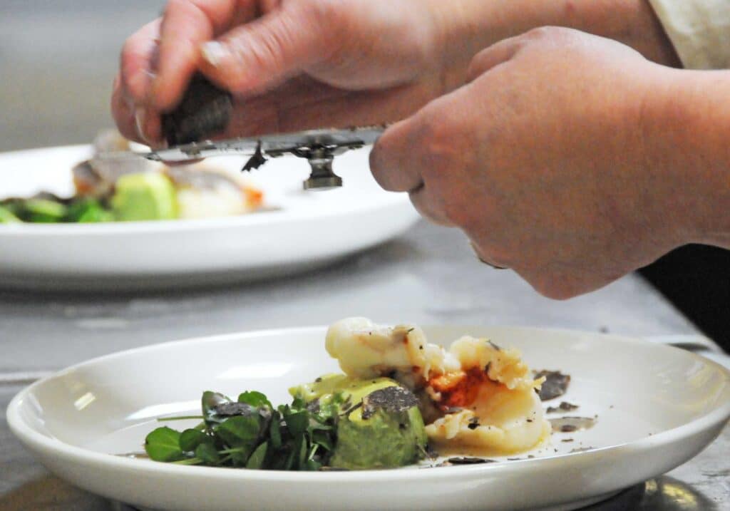 Chef grating truffle over a gourmet dish at the famed Truffle Feast of Barboursville Vineyards in Virginia prepared by Palladio.